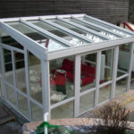 ogród zimowy ze stołem i czerwoną kanapą