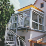 żółty zadaszony taras na piętrze z wejściem po skrętnych schodach